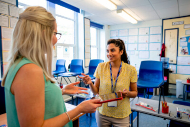 Two teachers talking in a school classroom